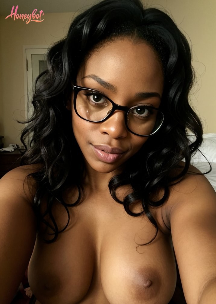 This image is a close-up of a person, presumably a woman, with a medium to dark skin tone. She is wearing black-rimmed glasses and has a confident, direct gaze towards the camera.…